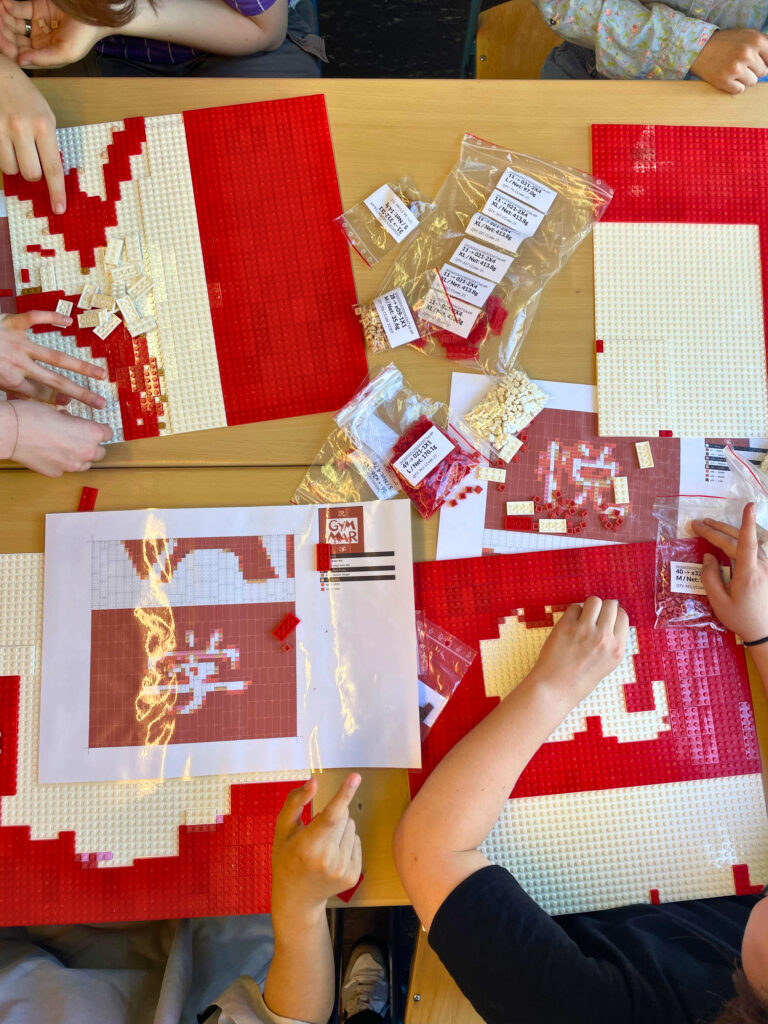 Schülerinnen und Schüler gestalten gemeinsam ein Mosaik im Rahmen des Gymmar-Schulprojekts.